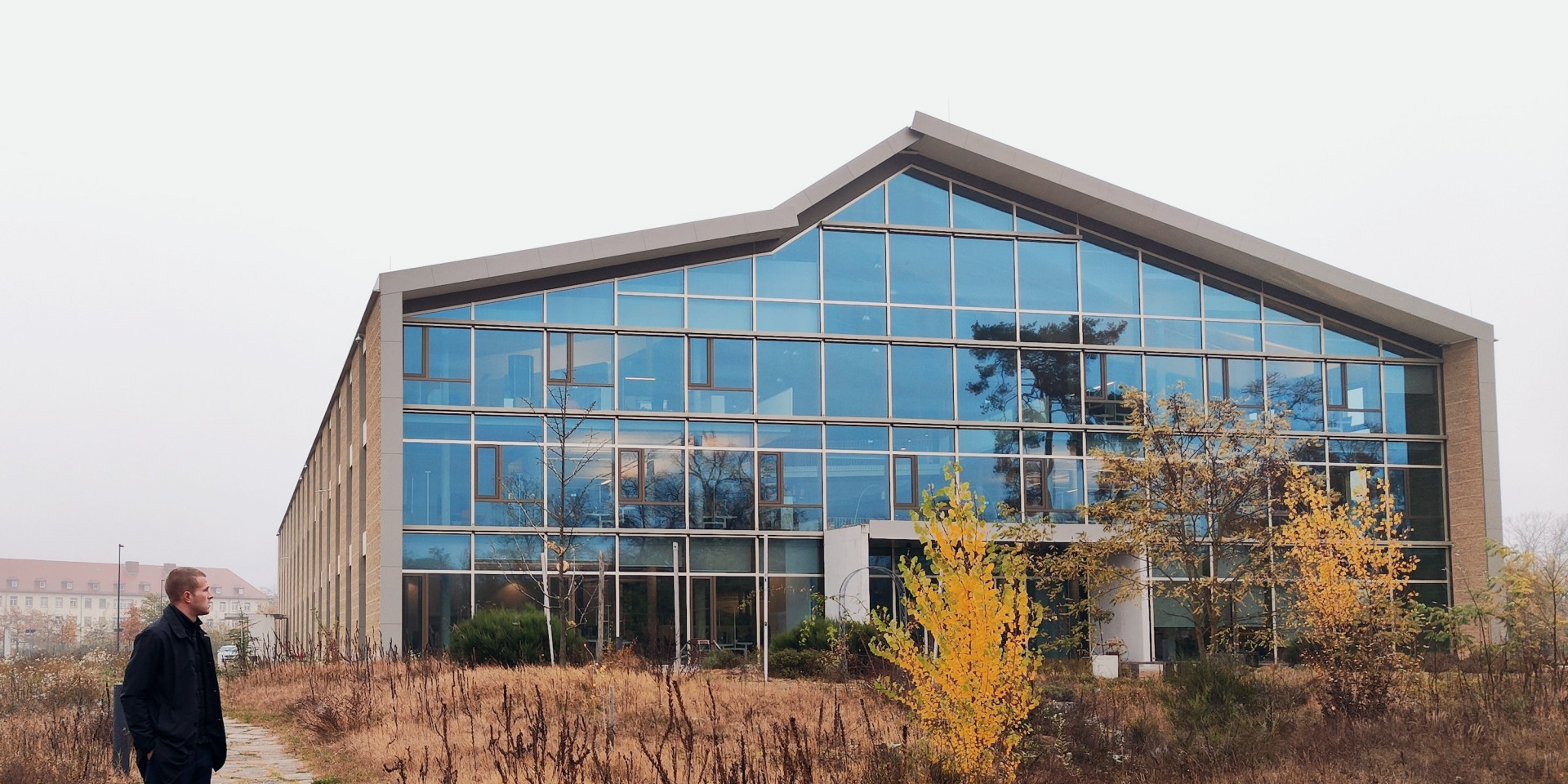 Ein modernes Haus mit viel Glas, ein Student steht davor