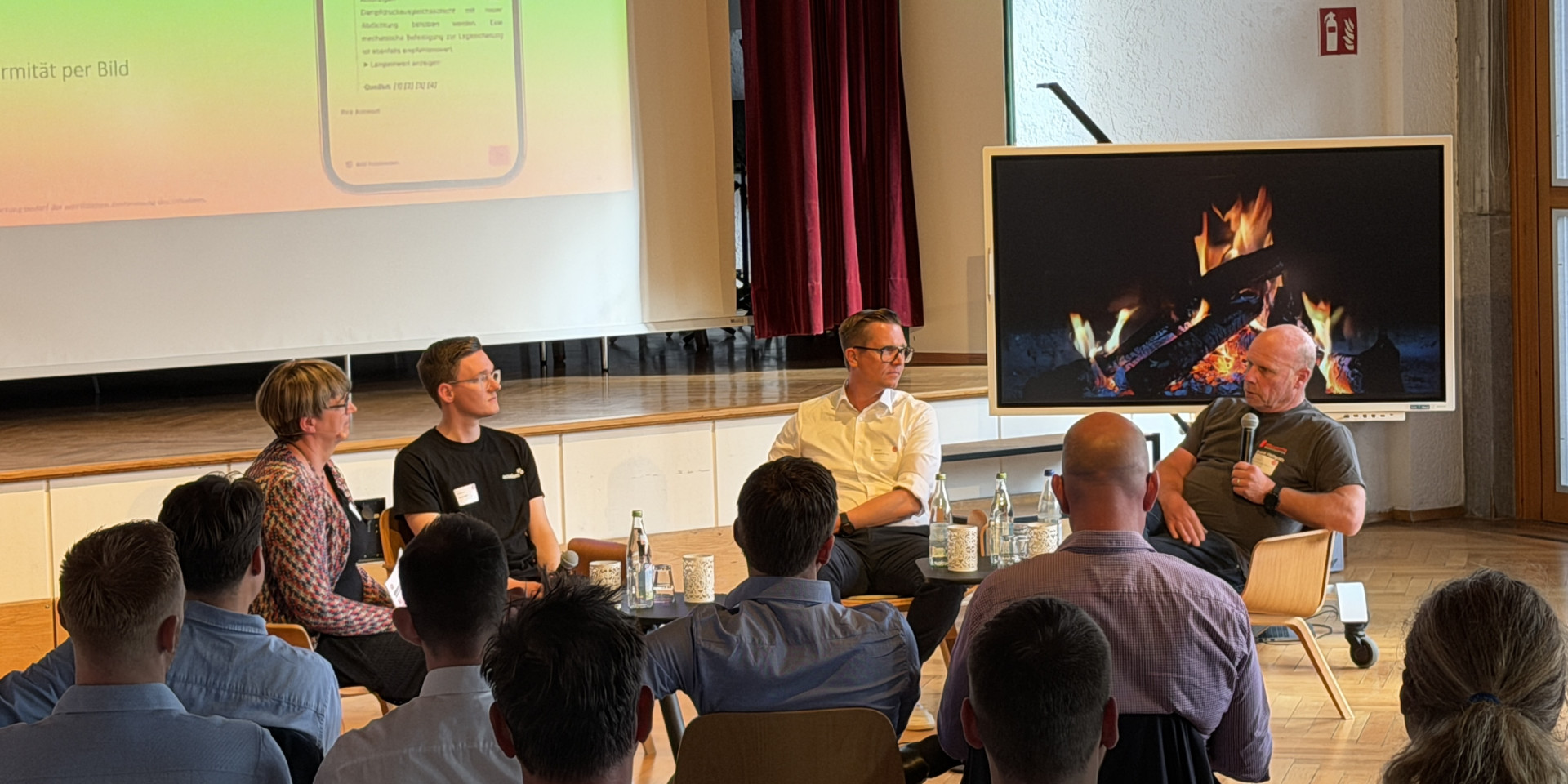 Personen sitzen bei einer Podiumsdiskussion vor Publikum