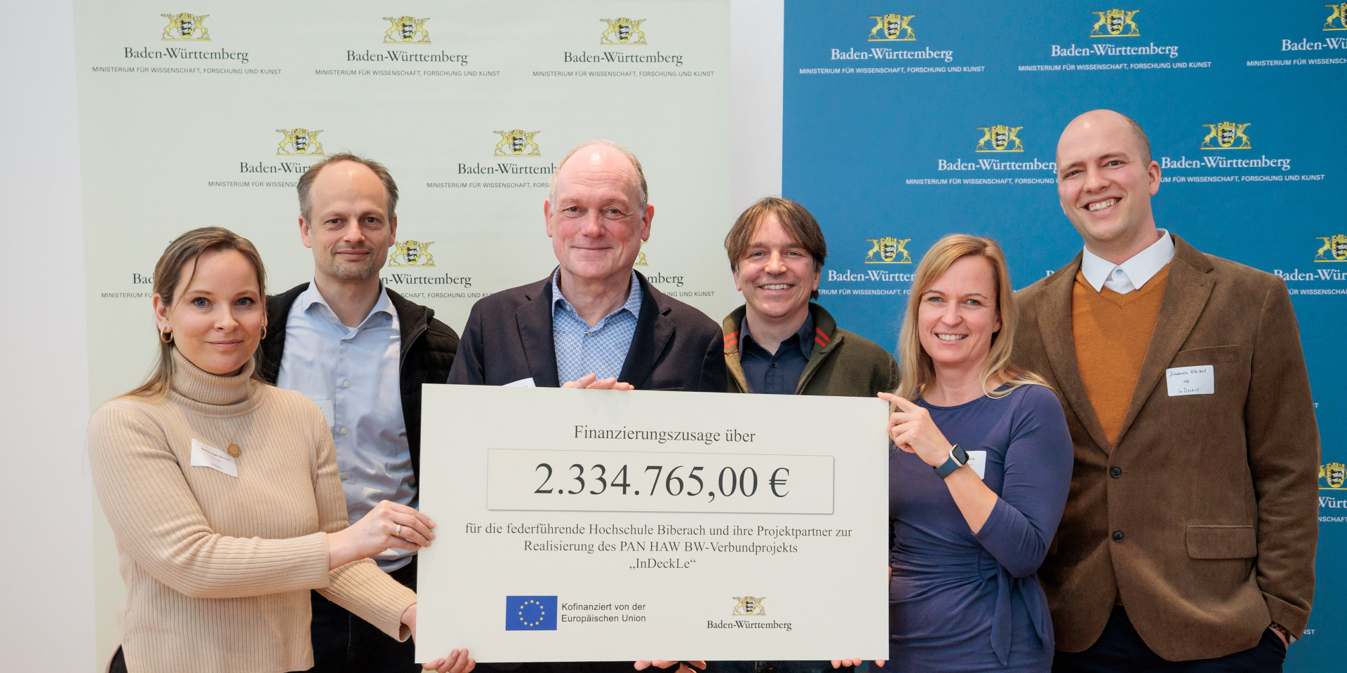 Sechs Personen halten Scheck hoch