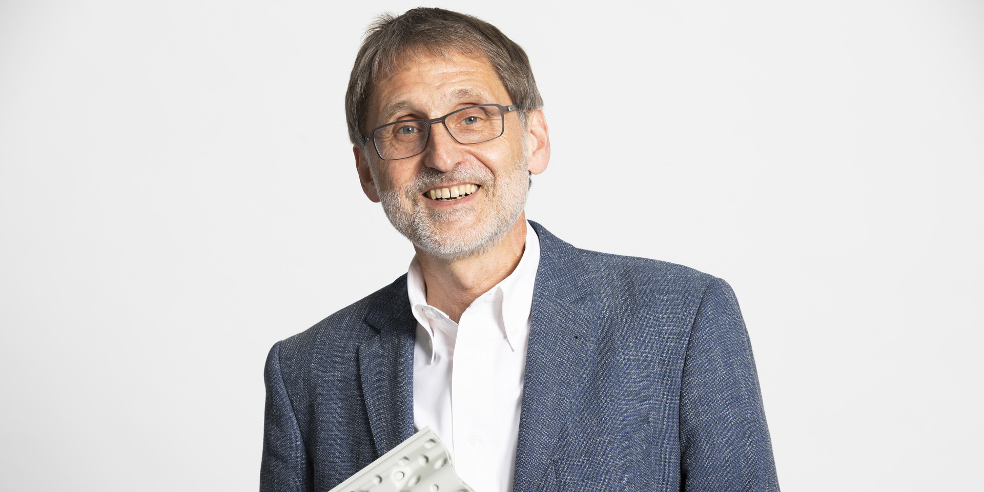 Ein Mann hält etwas in der Hand und lacht in die Kamera