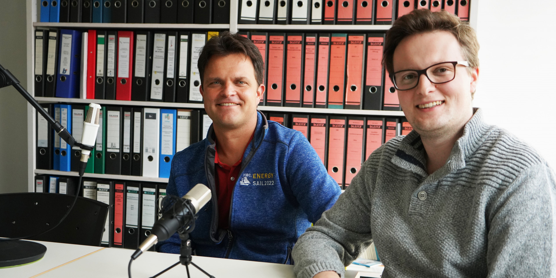 Zwei Männer an einem Tisch bei Podcastaufnahme