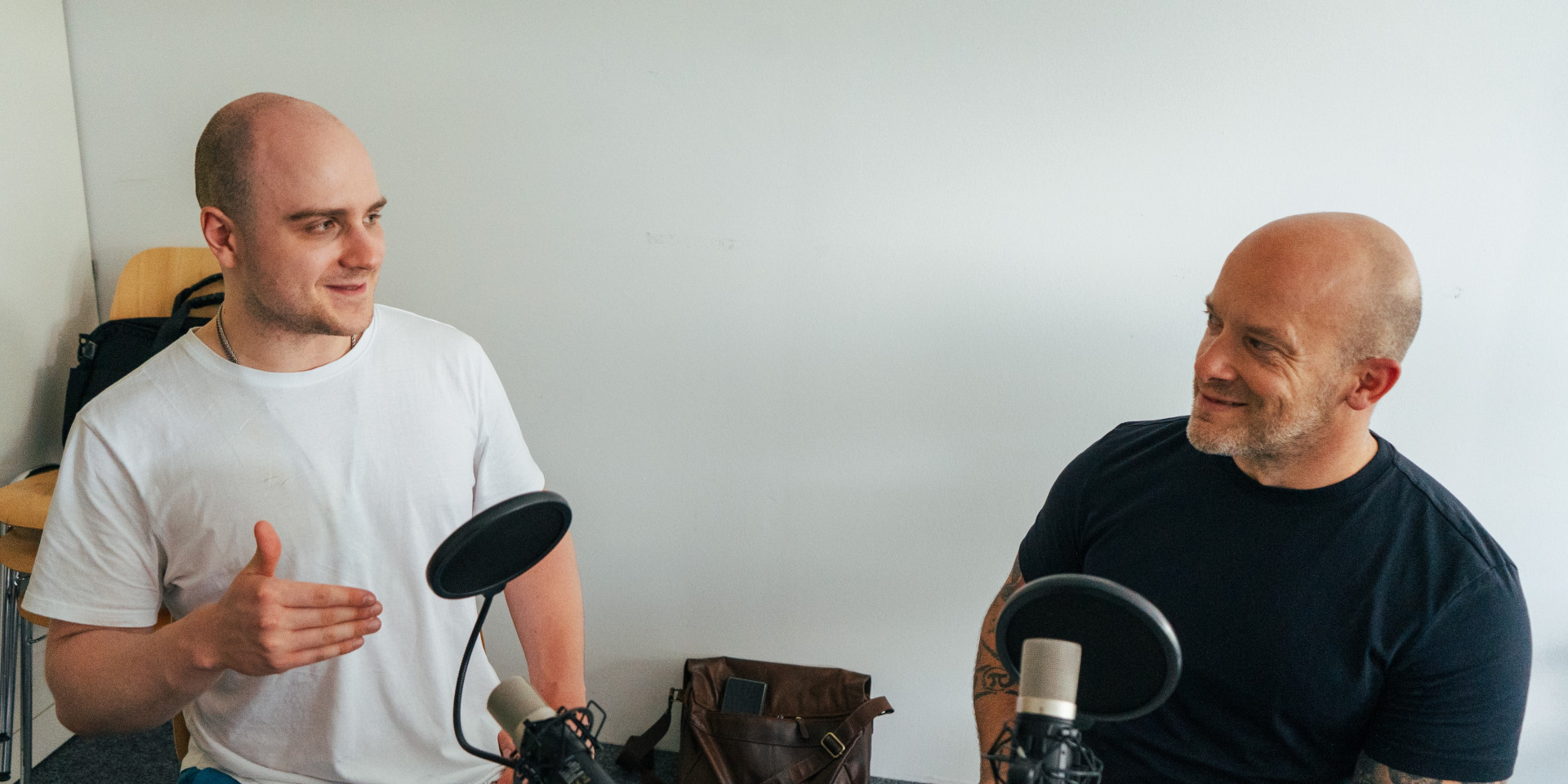 Zwei Männer sitzen an einem Tisch bei einer Podcastaufnahme