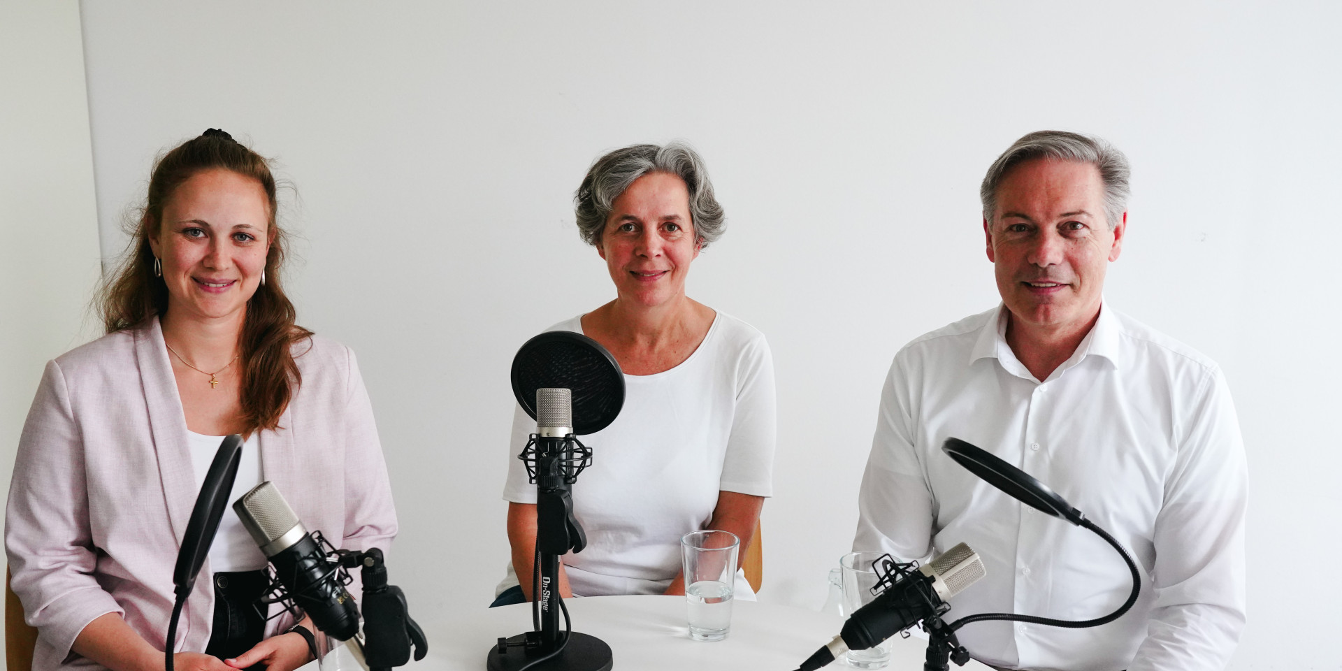 Drei Personen sitzen bei einer Podcast-Aufnahme