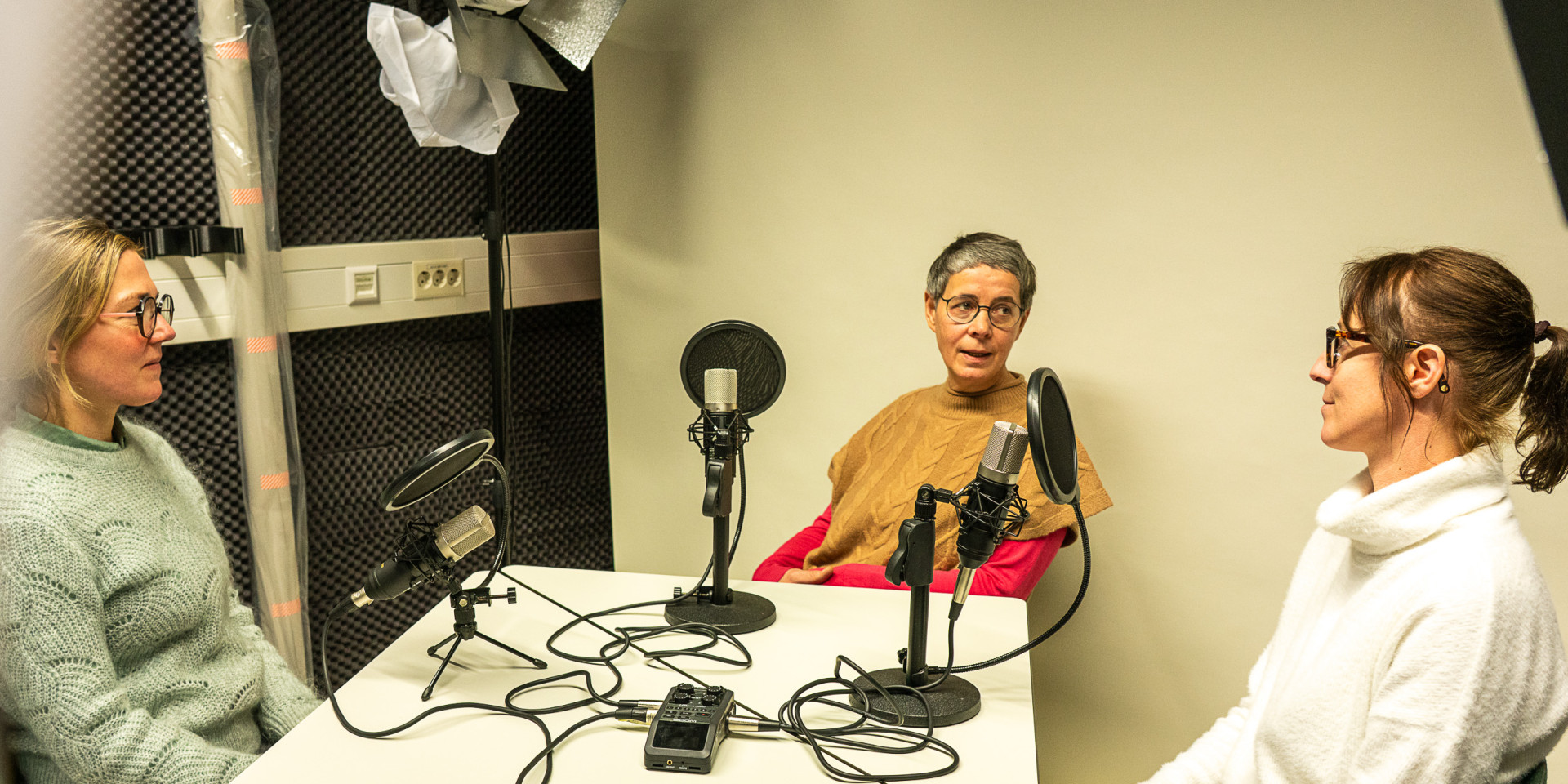 Drei Frauen sitzen bei einem Podcast am Tisch 