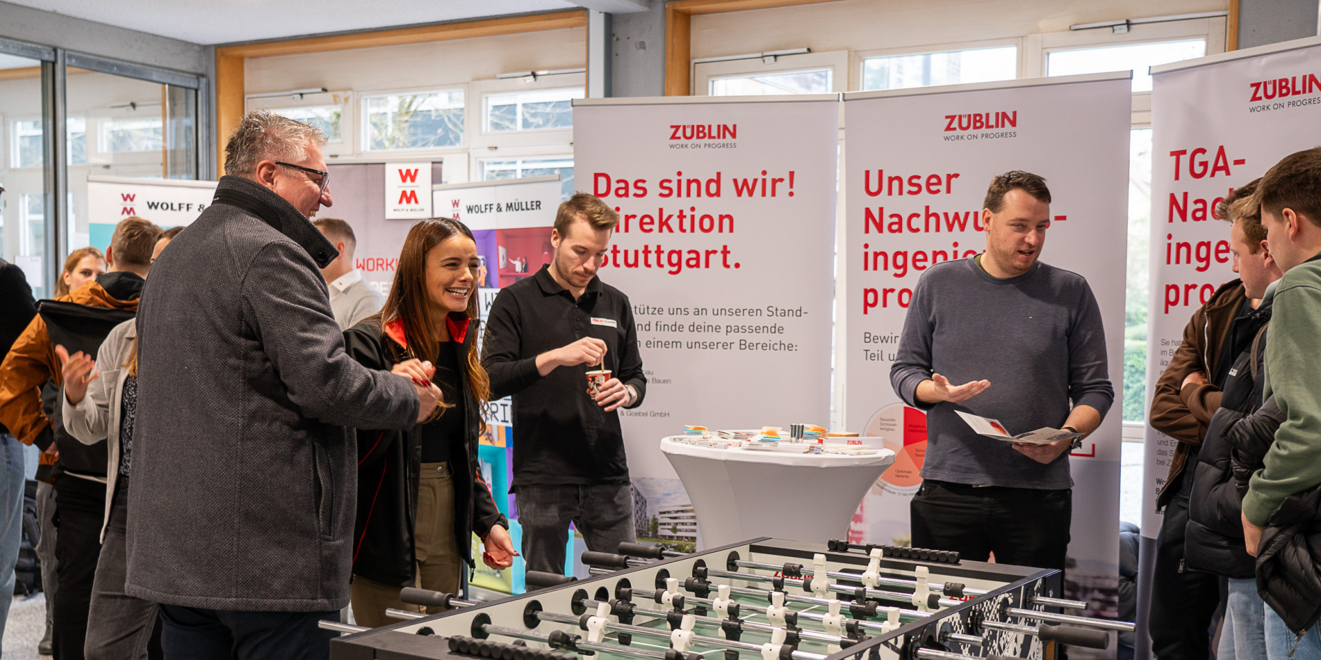 Viele Personen stehen auf einer Messe an einem Kickertisch