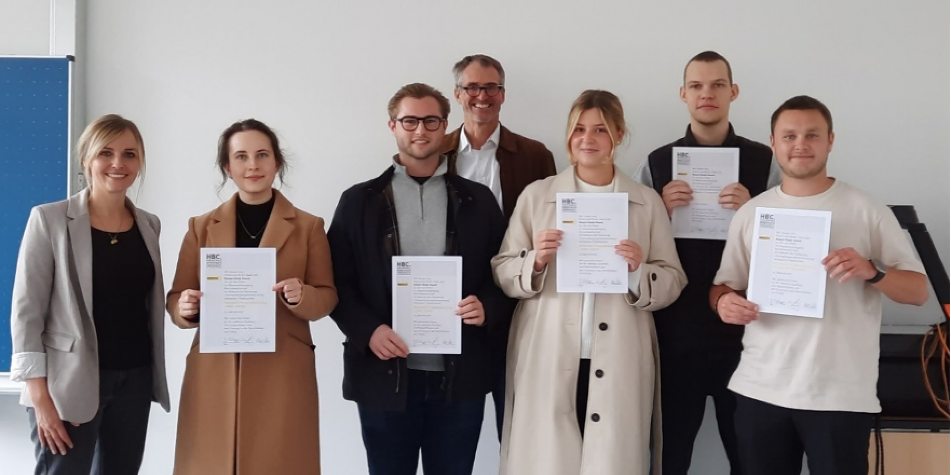 7 Personen mit Urkunden in der Hand