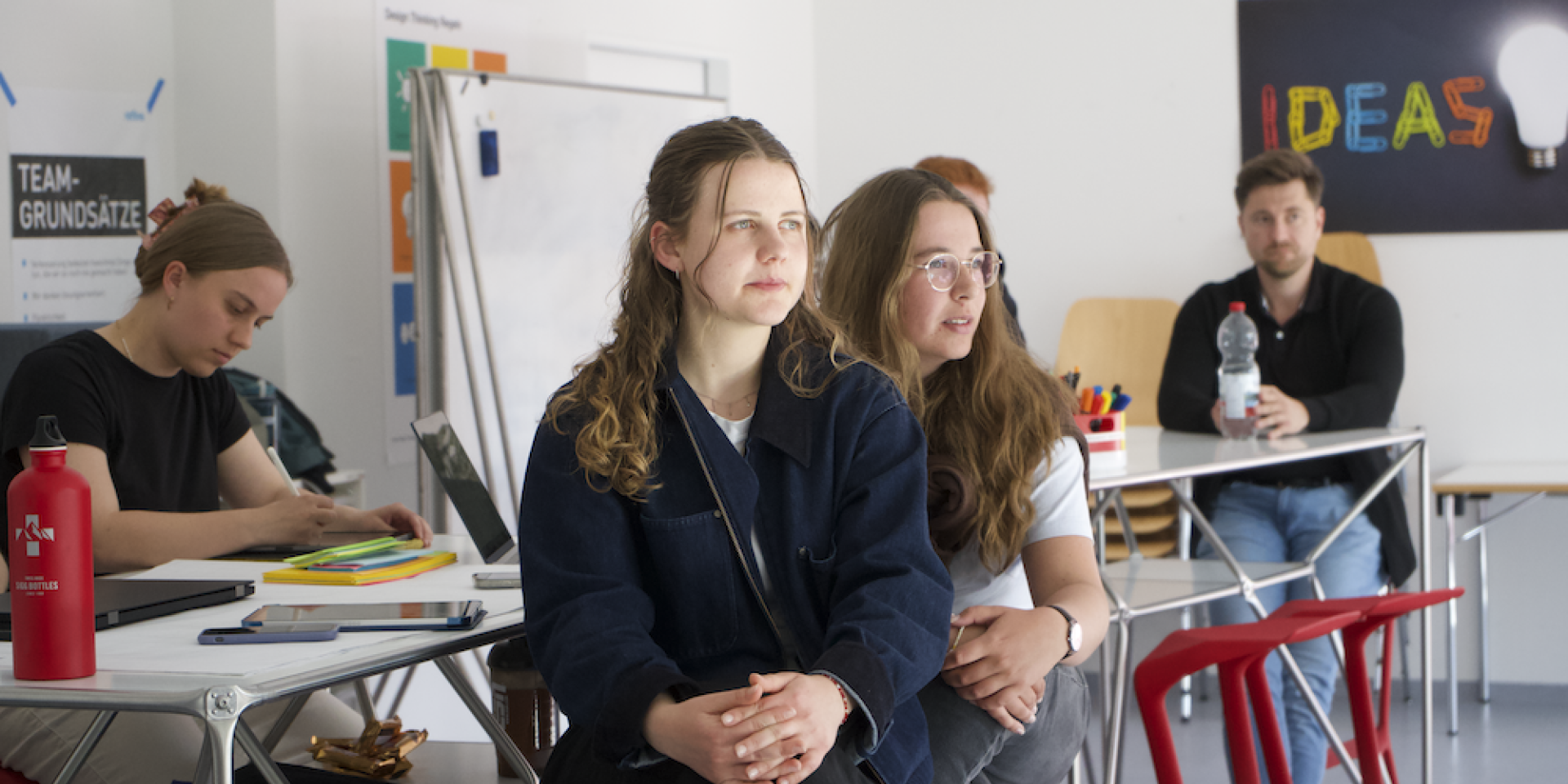 Studierende sitzen an Tischen
