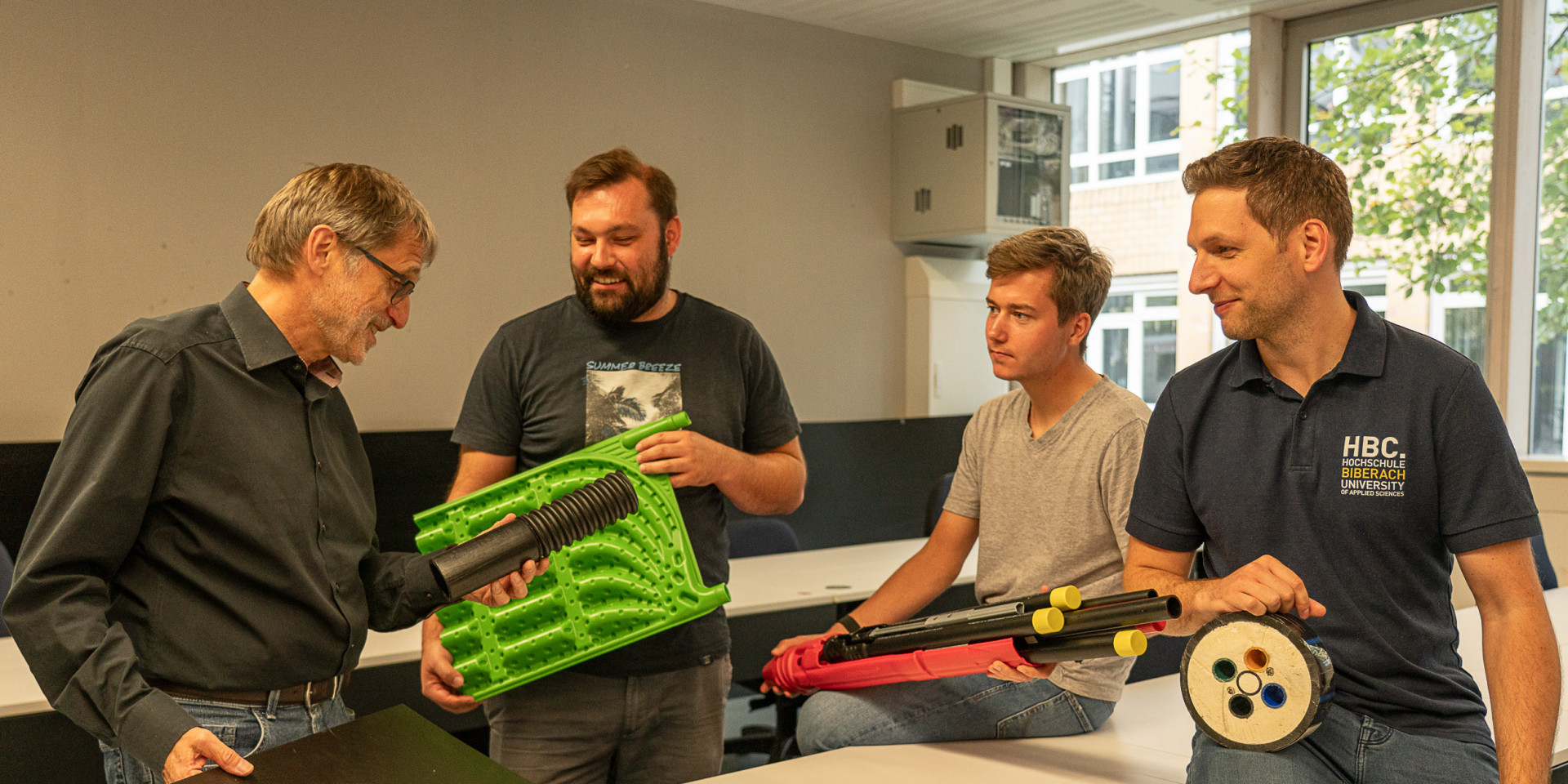 Vier Männer zeigen technisches Material 