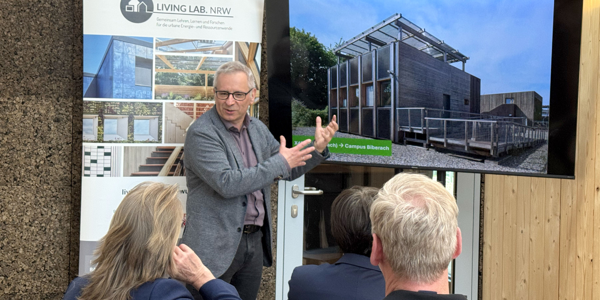 Ein Mann steht vor einem Bildschirm und erklärt etwas