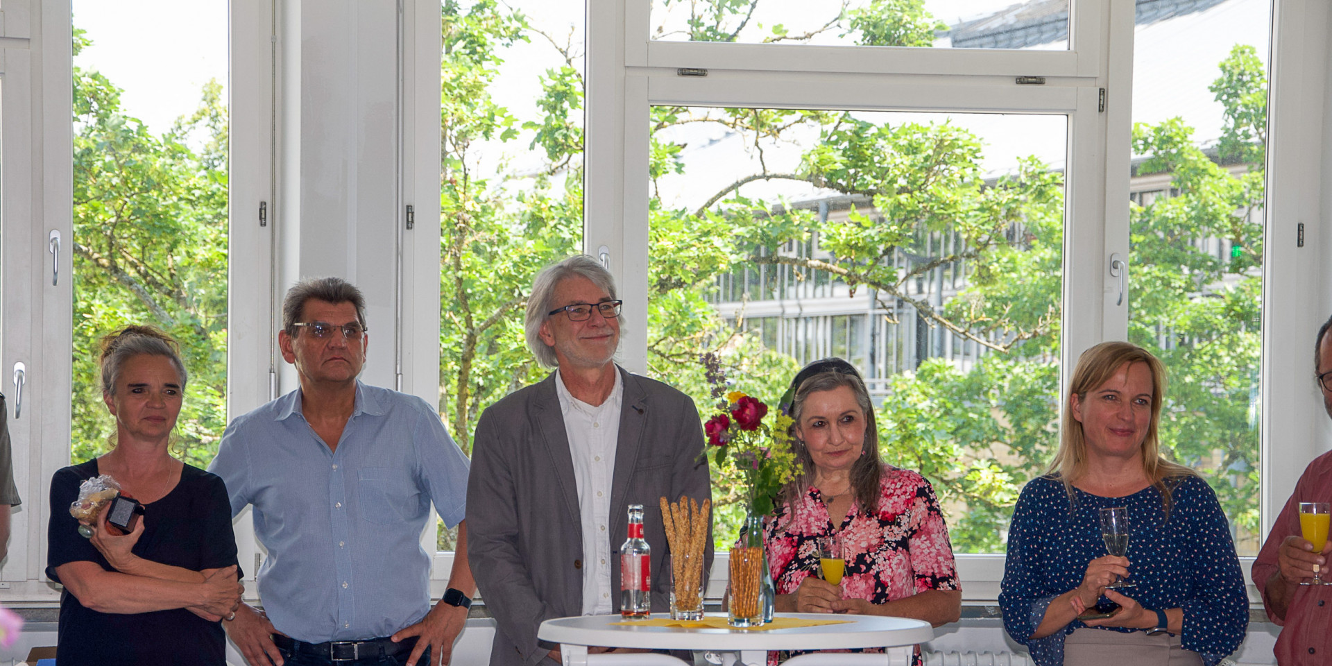 Fünf Erwachsene stehen in einer Reihe bei einer festlichen Veranstaltung