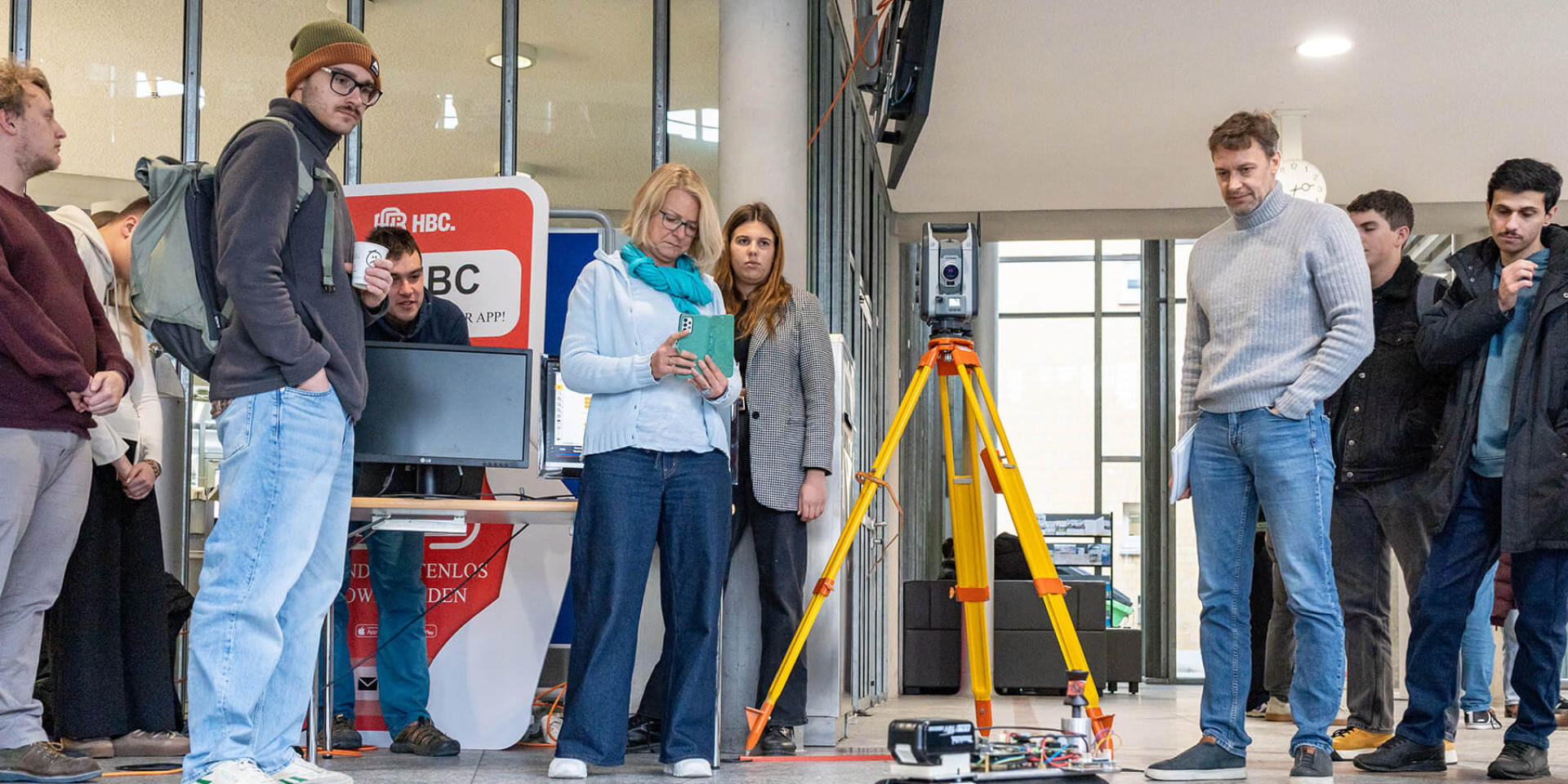 Eine Gruppe Studierender und Professor*innen steuert und filmt einen autonomen Roboter für die Baustelle