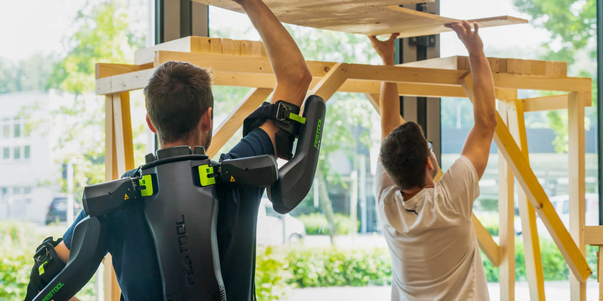 Zwei Studierende arbeiten Überkopf mit Exoskelett