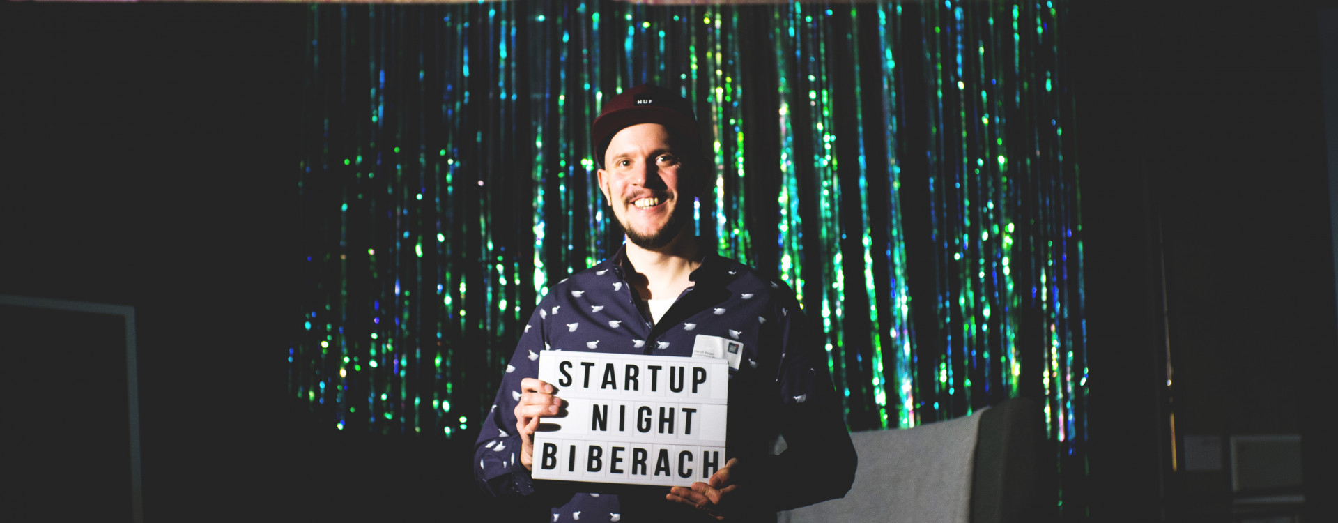 Mann vor glitzerndem Hintergrund mit Schild in der Hand