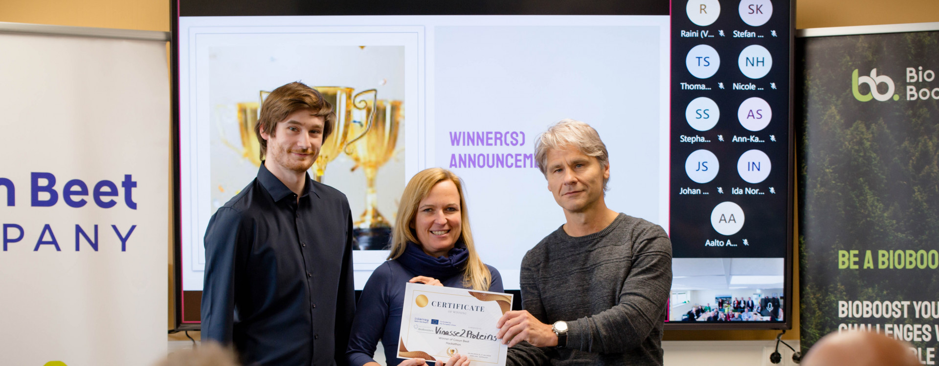 Ein Mann übergibt Urkunde an eine Frau und einen Mann