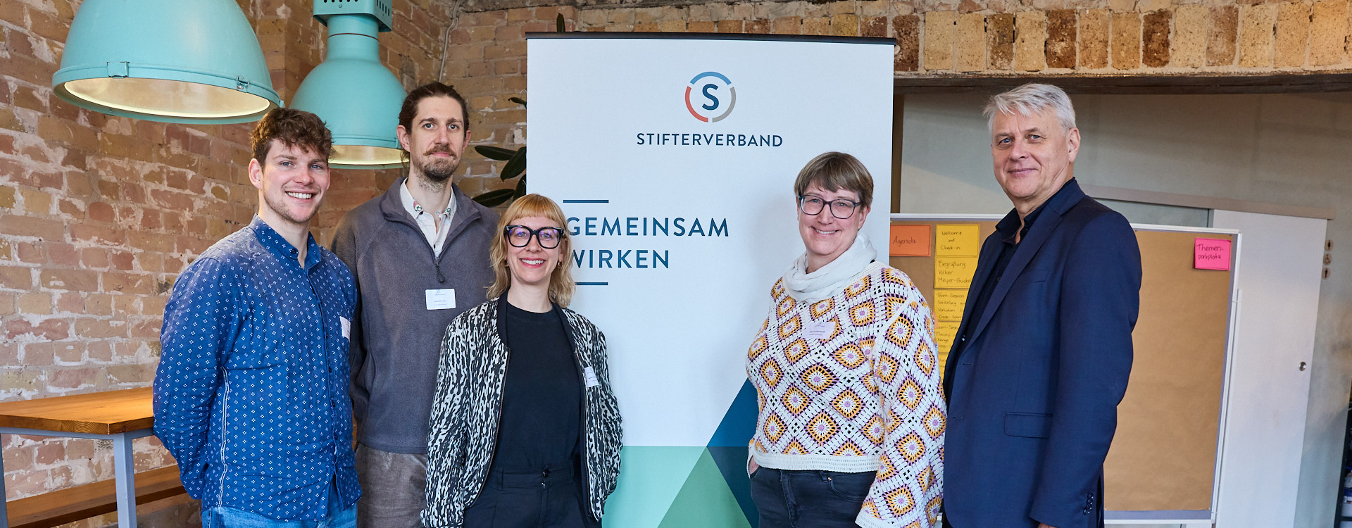 Fünf Personen stehen vor einem Banner
