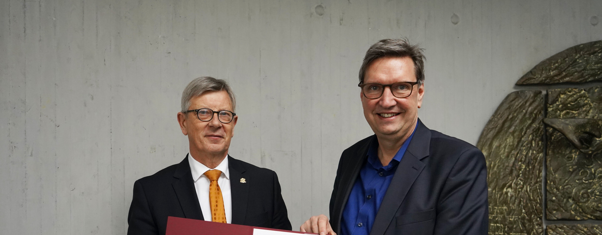 Übergabe Urkunde zwischen zwei Männern