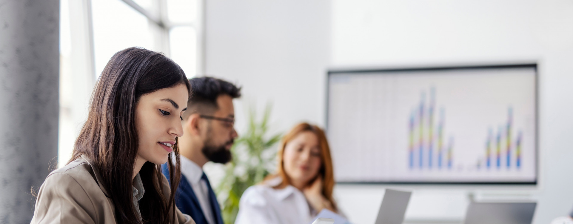 Drei Personen sitzen mit Laptops an einem Tisch