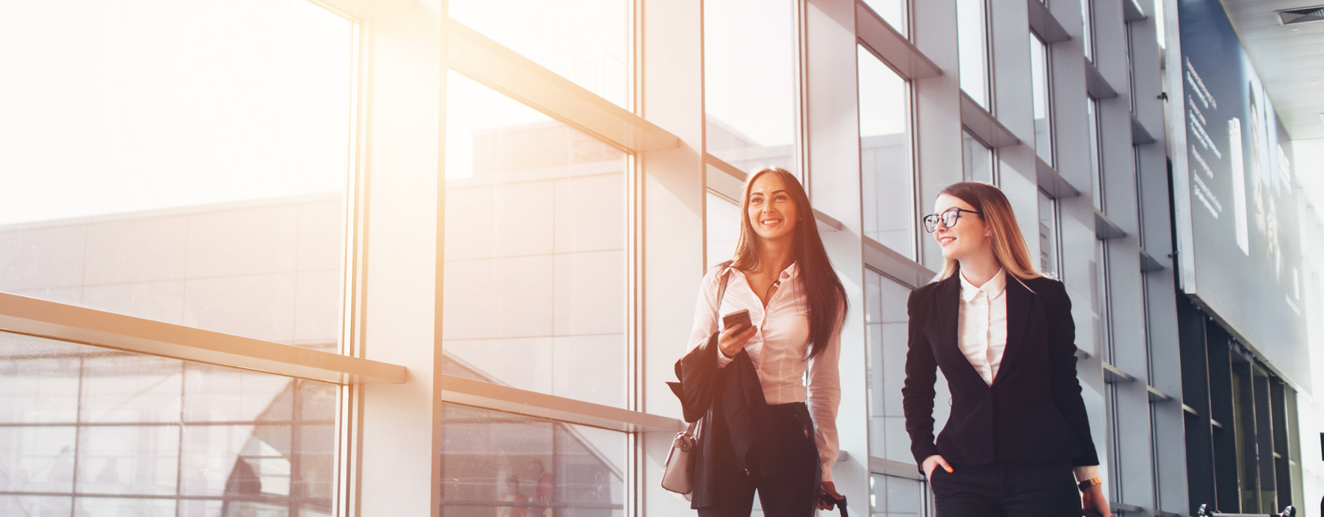 Zwei Frauen ziehen einen Koffer, sie sind auf einer Businessreise