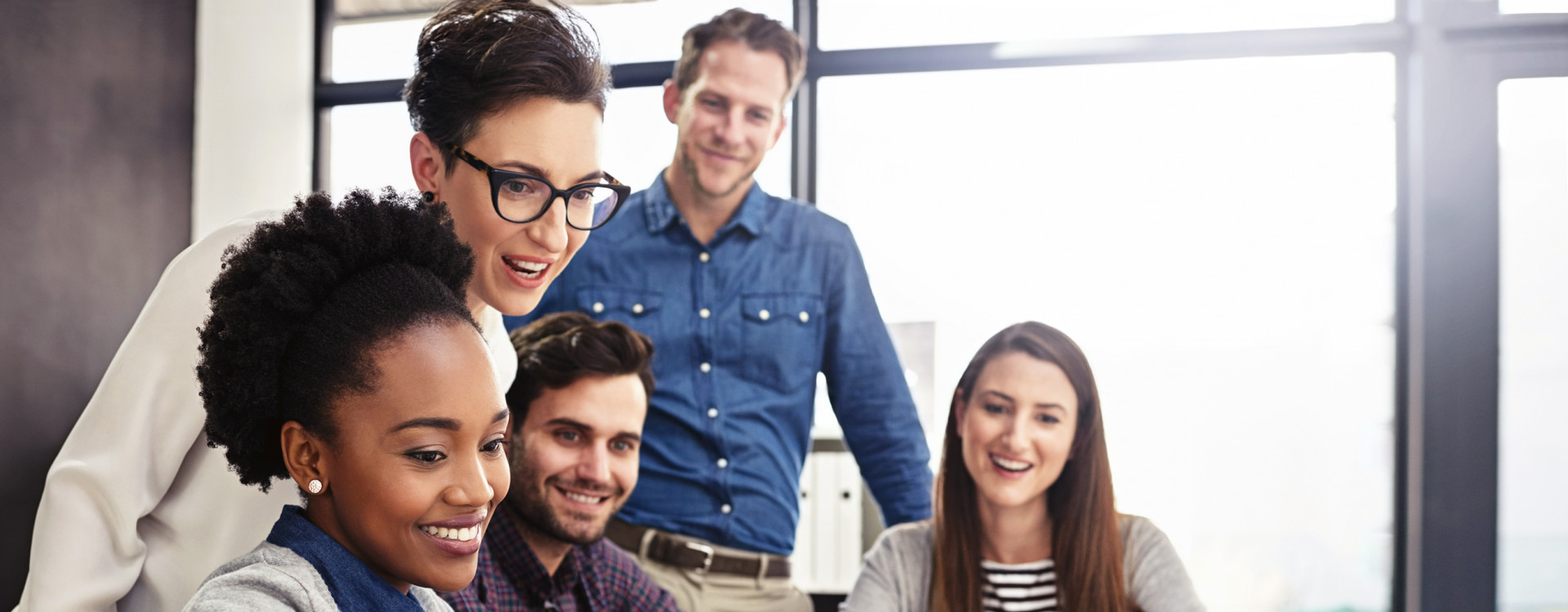 Fünf Personen verschiedener Nationalität sitzen vor einem Laptop