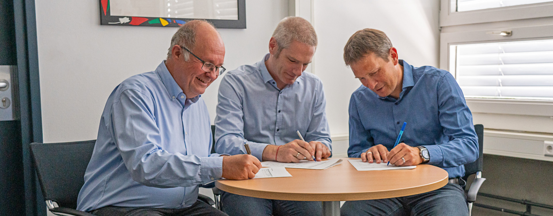 drei Männer unterzeichnen Vertrag an Tisch