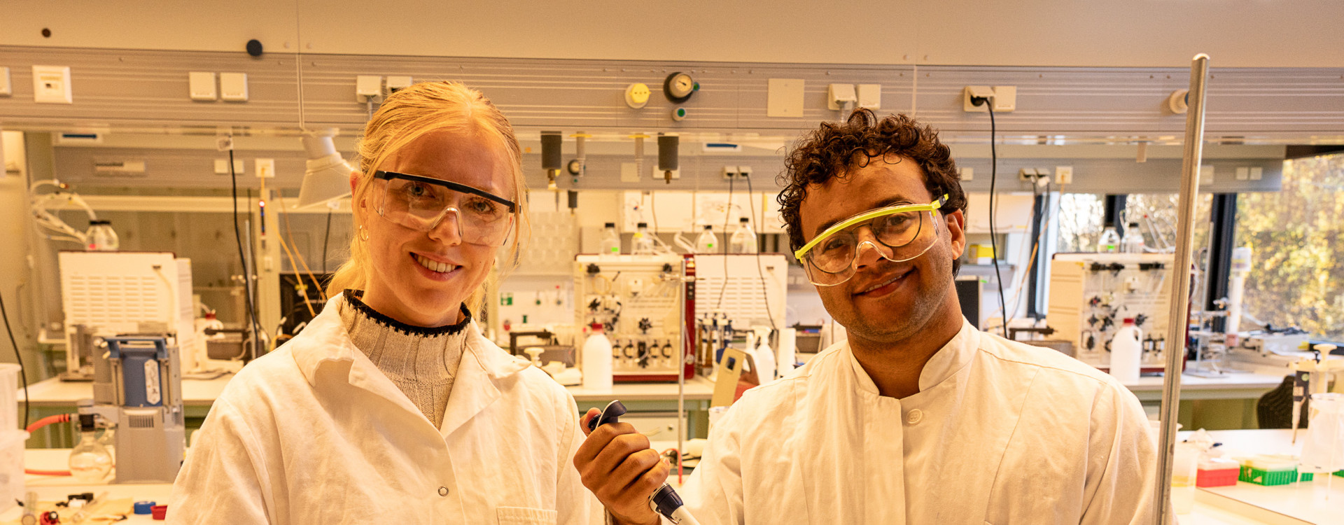 Eine junge Frau und ein junger Mann stehen im Labor und arbeiten