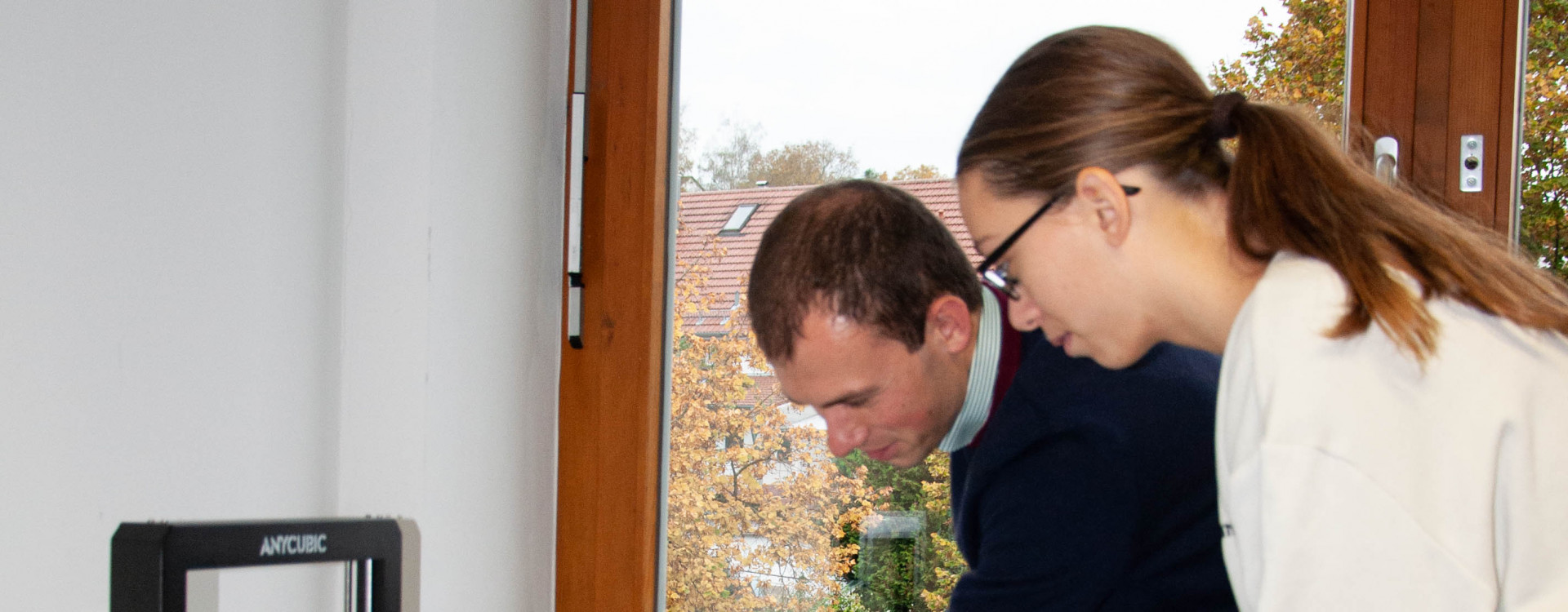 Mitarbeiter erklärt Schülerin 3-D-Drucker