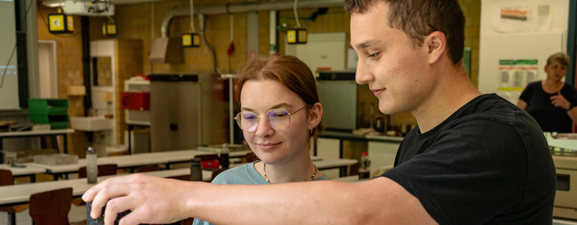 Eine junge Frau und ein junger Mann stehen im Labor für Straßenbau