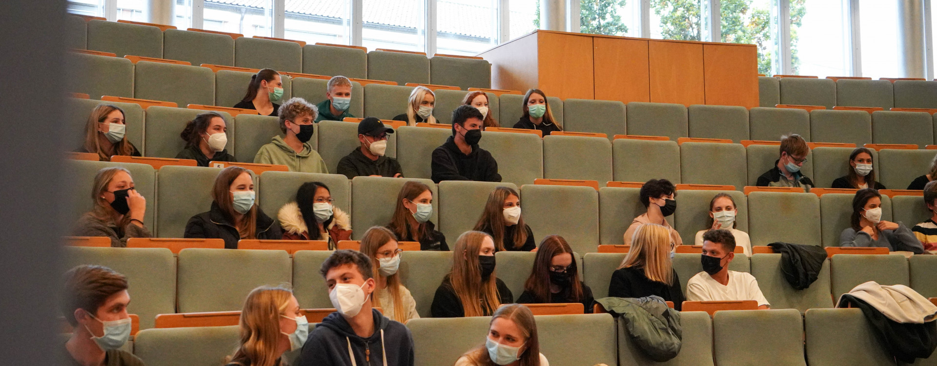 Studierende in großem Hörsaal mit Masken