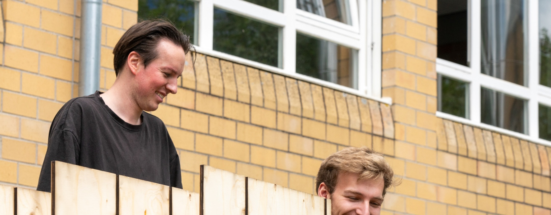Zwei Studierende bauen ein Pavillon aus Holz auf