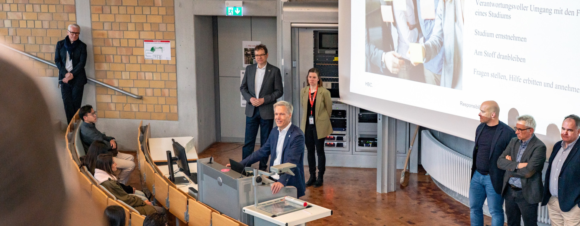 Prof. Bahr steht im Hörsaal und begrüßt Studierende