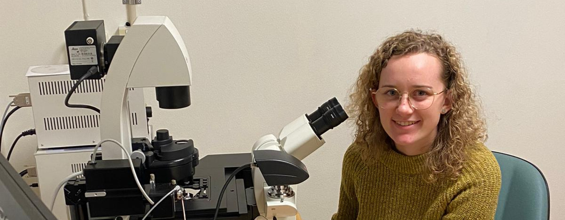 Junge Frau sitzt vor Mikroskop