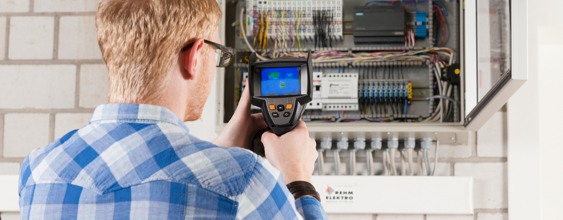 Student mit Ablesegerät vor einem Stromkasten