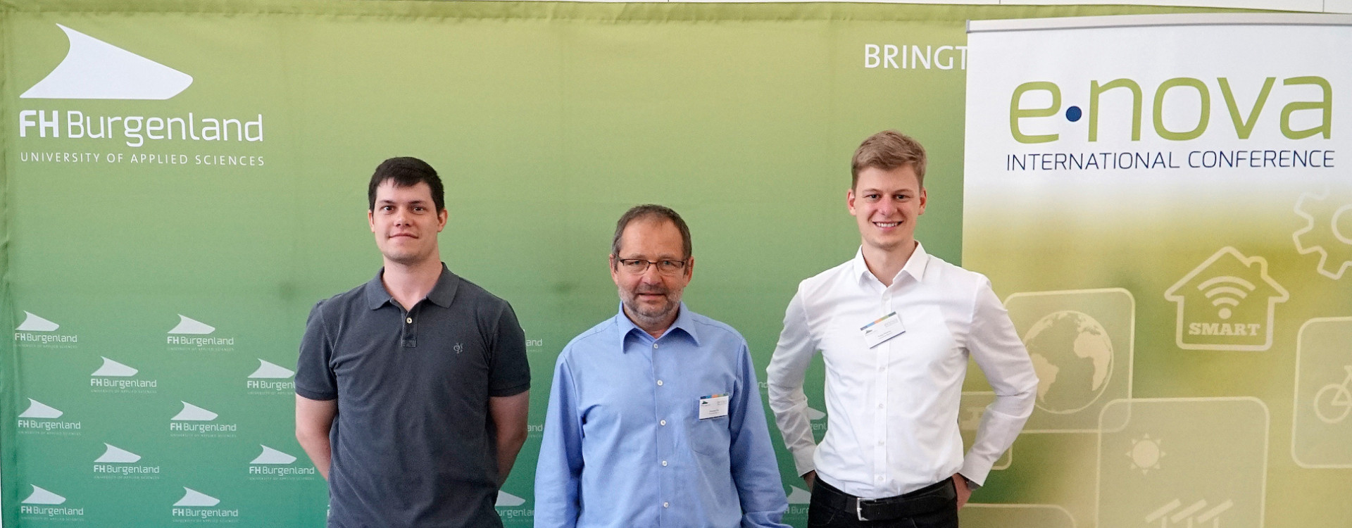 Drei Personen vor Banner e-nova Kongress