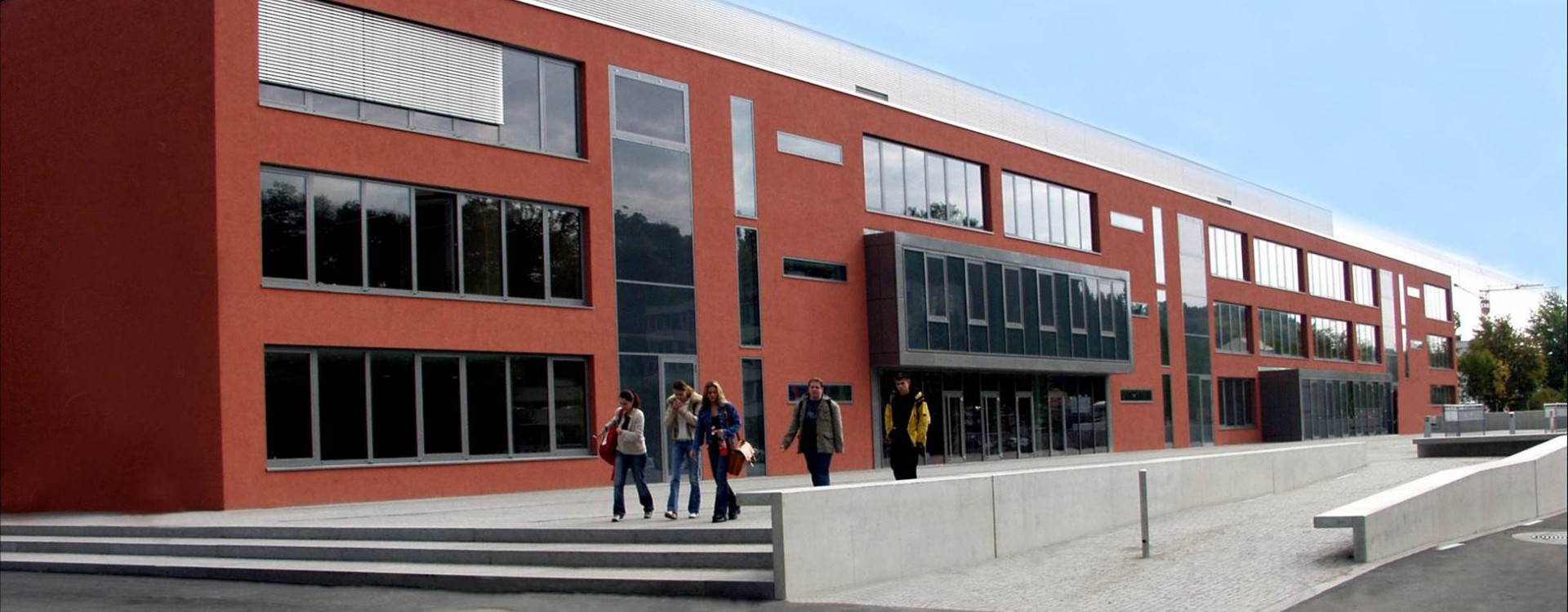Rotes Gebäude, Schule, mit Personen davor