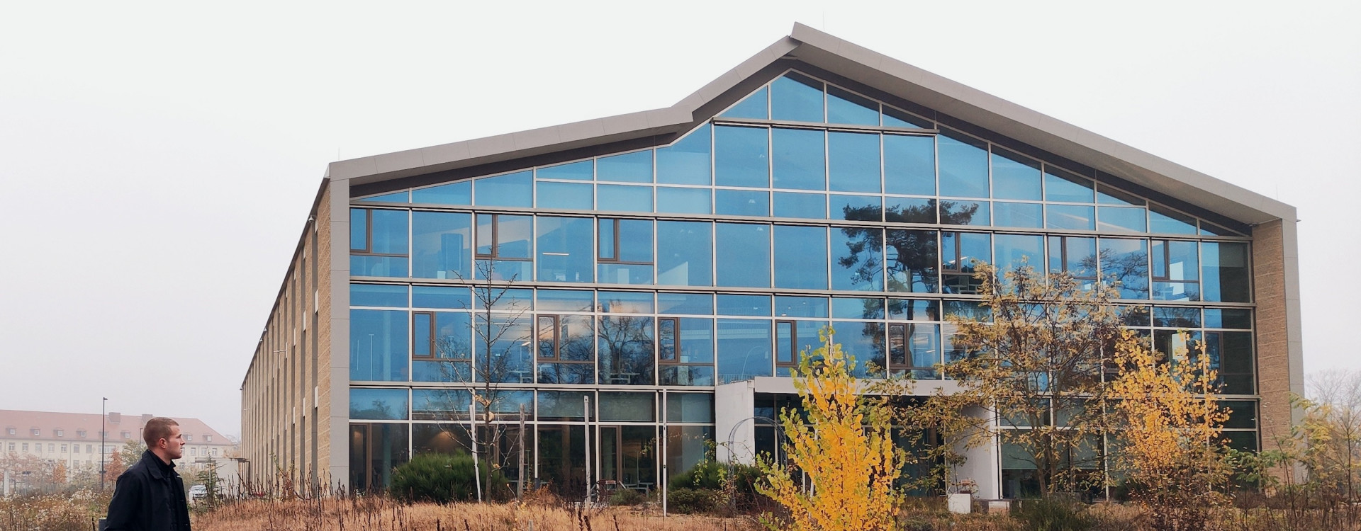 Ein modernes Haus mit viel Glas, ein Student steht davor
