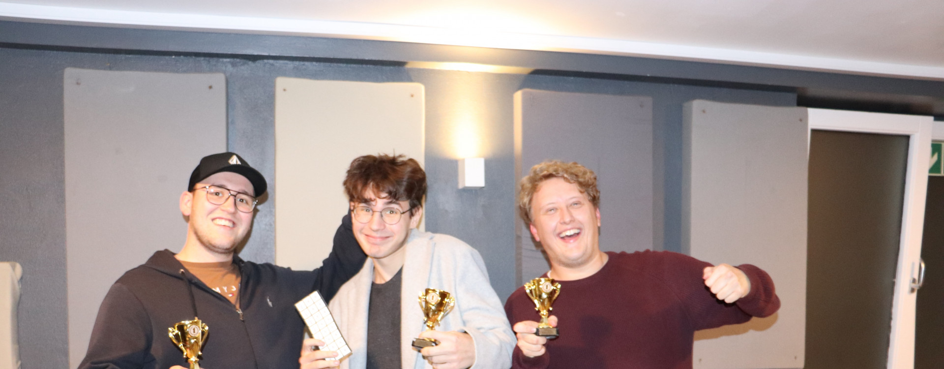 Drei Studenten mit Pokalen in der Hand, freuen sich über den Gewinn bei der KI Werkstatt Night