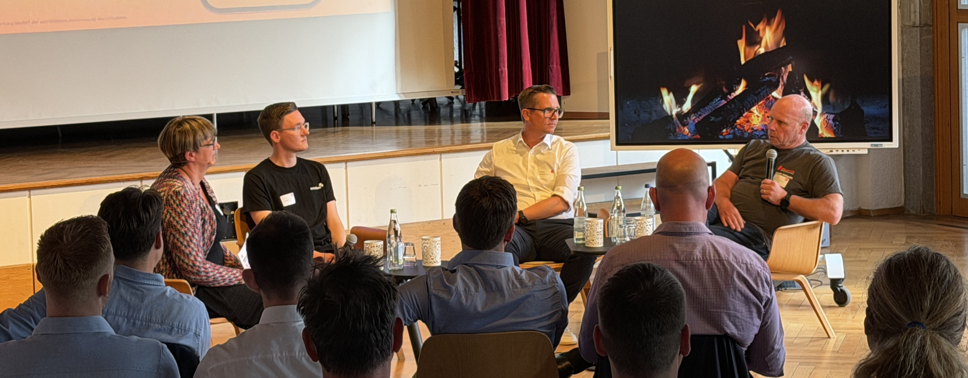 Personen sitzen bei einer Podiumsdiskussion vor Publikum