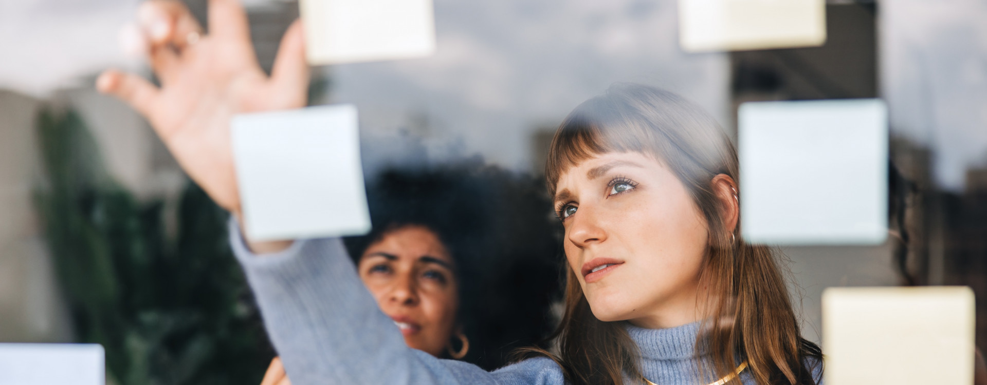 Zwei Frauen kleben Postits auf