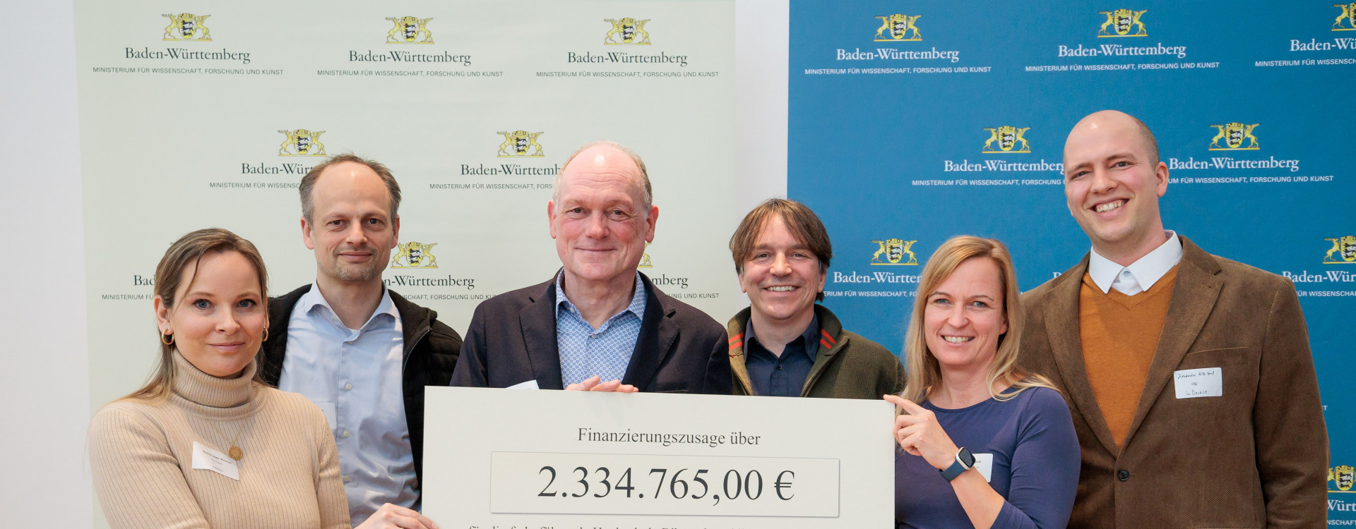 Sechs Personen halten Scheck hoch