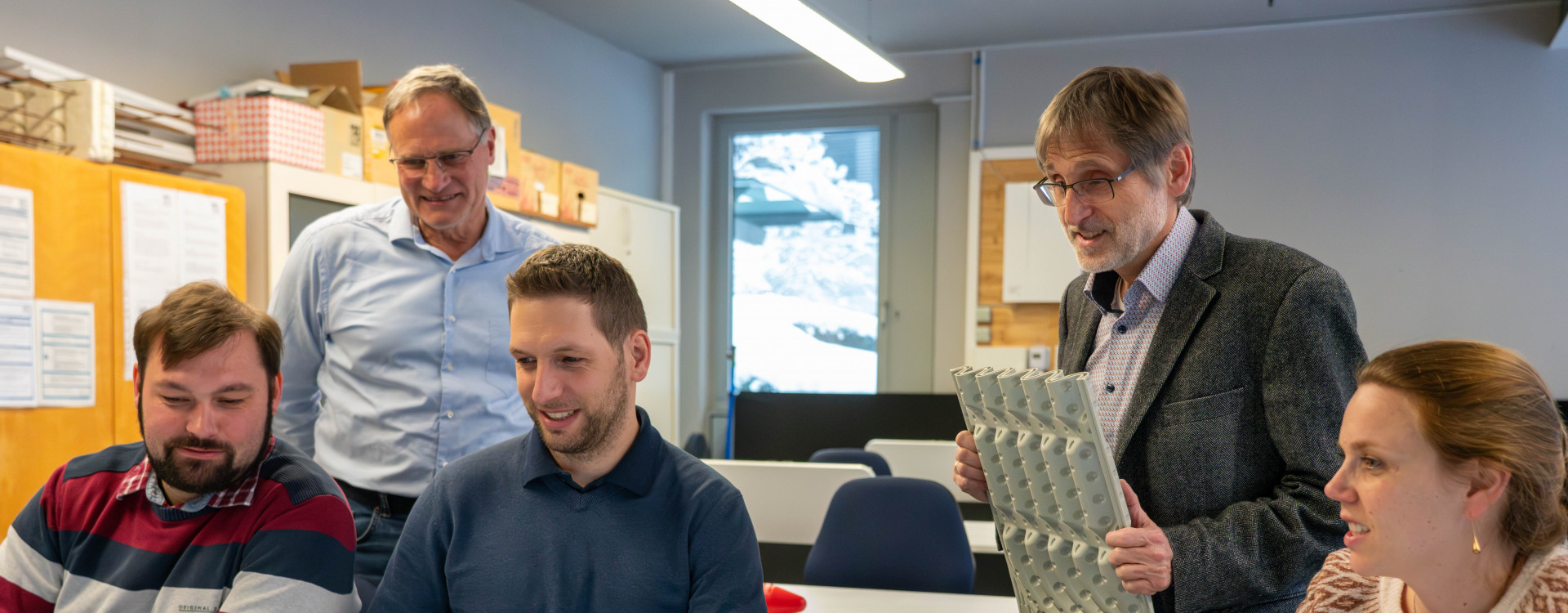 Fünf Mitarbeiter*innen sitzen vor einem Bildschirm