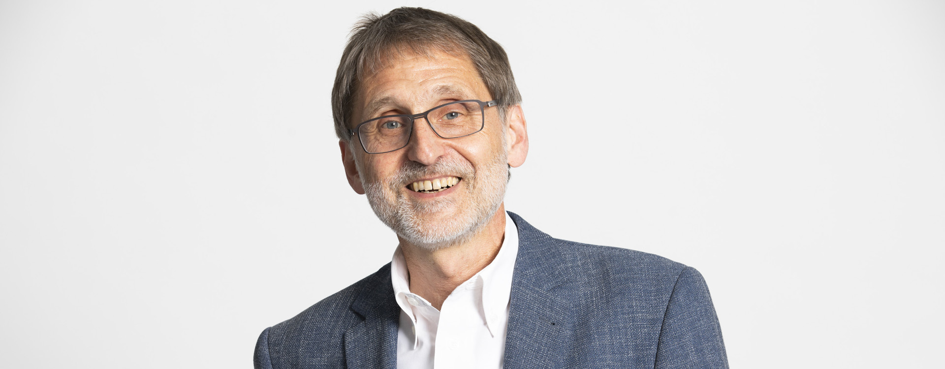 Ein Mann hält etwas in der Hand und lacht in die Kamera