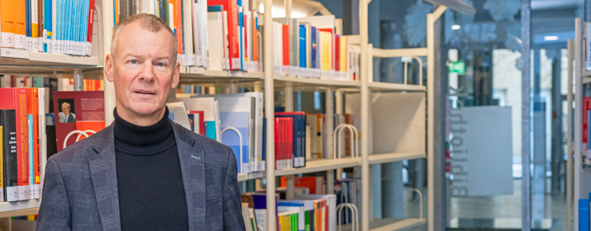 Mann im Bibliothek hält Buch hoch