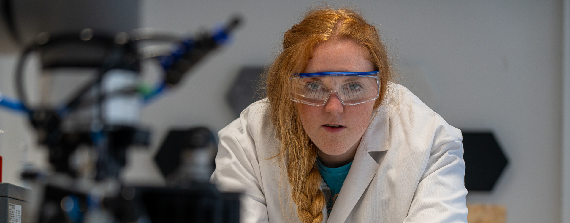 Frau steht vor Roboterarm im Labor