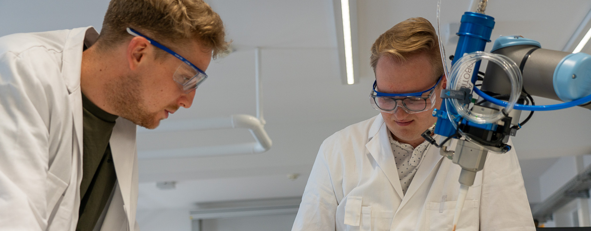 Zwei Männer im Labor arbeiten an einem Roboterarm