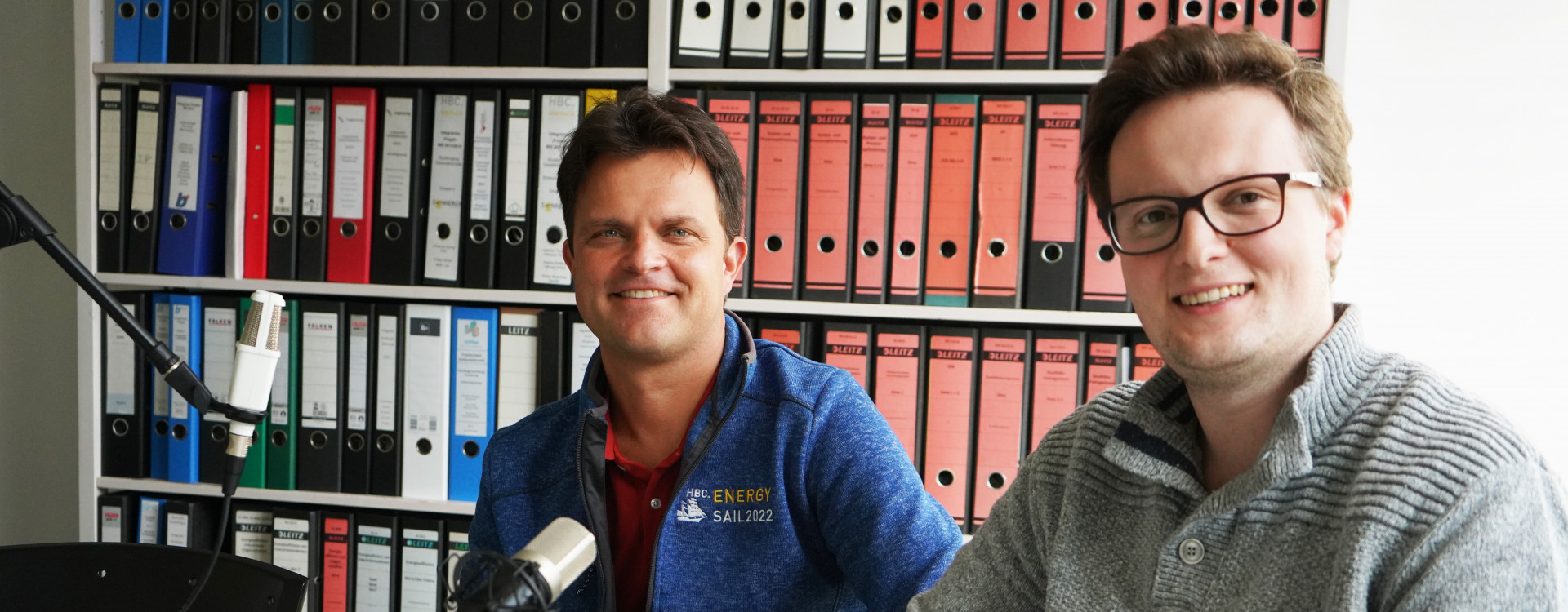 Zwei Männer an einem Tisch bei Podcastaufnahme