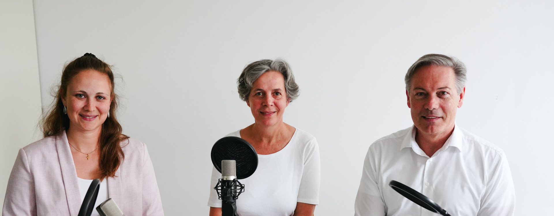 Drei Personen sitzen bei einer Podcast-Aufnahme