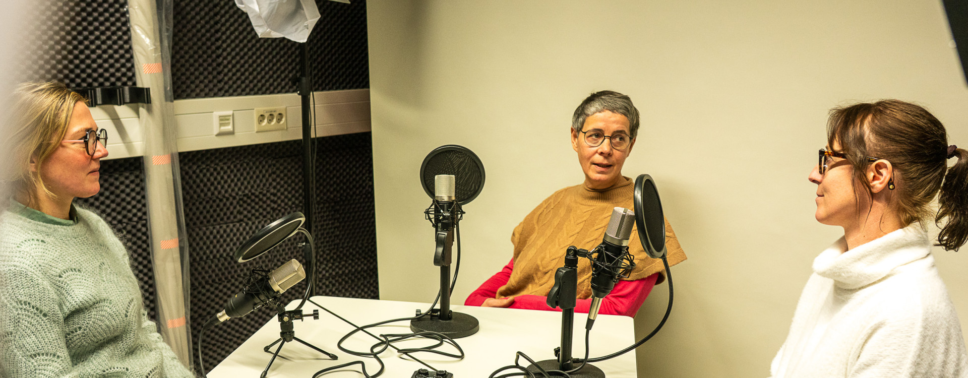 Drei Frauen sitzen bei einem Podcast am Tisch