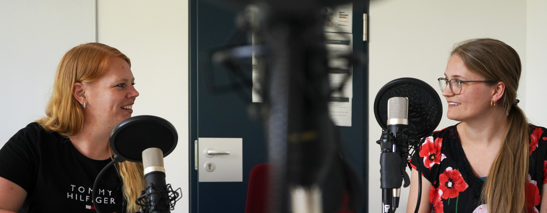 Zwei Frauen sitzen am Mikrofon bei Podcastaufnahme