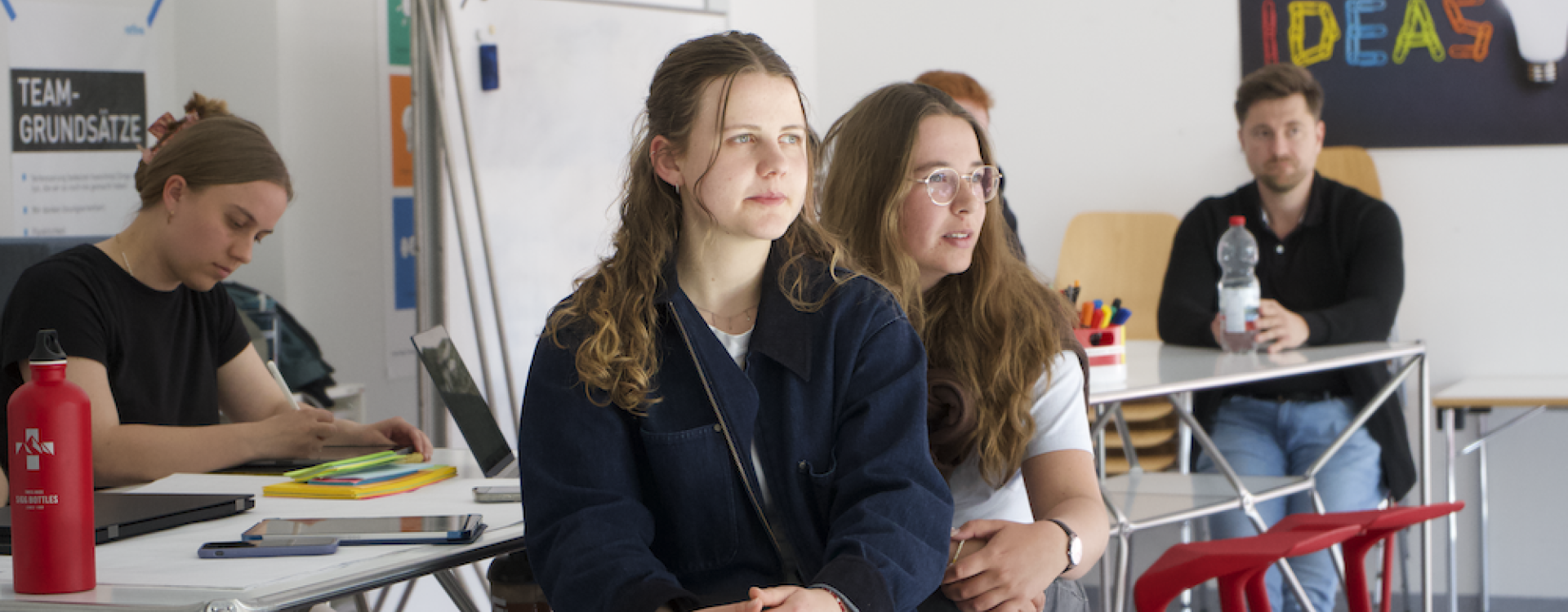 Studierende sitzen an Tischen