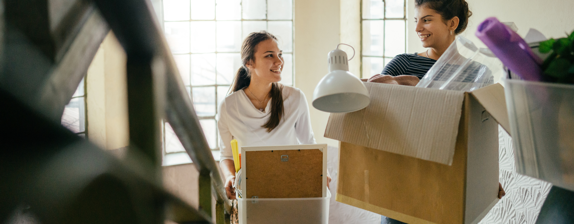 Zwei Frauen tragen Umzugskartons